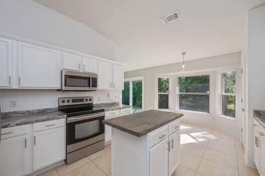 430 Hatchee Dr, Crestview, FL 32536 - kitchen with stainless steel appliances, white cabinetry, light tile patterned flooring, dark countertops, and vaulted ceiling