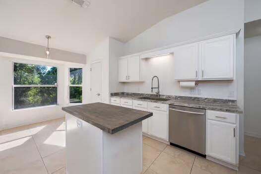 430 Hatchee Dr, Crestview, FL 32536 - kitchen featuring stainless steel dishwasher, a sink, vaulted ceiling, light tile patterned floors, and white cabinets