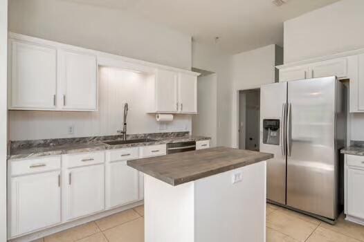 430 Hatchee Dr, Crestview, FL 32536 - kitchen featuring stainless steel refrigerator with ice dispenser, a sink, light tile patterned flooring, butcher block countertops, and white cabinetry