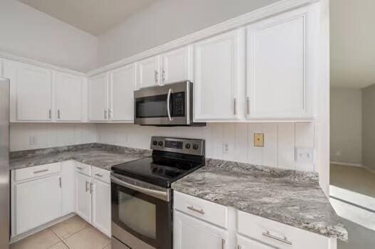 430 Hatchee Dr, Crestview, FL 32536 - kitchen with appliances with stainless steel finishes, white cabinets, light stone counters, and light tile patterned flooring