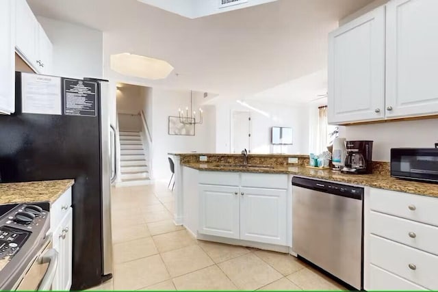 15100 Emerald Coast Pkwy Unit Ph4, Destin, FL 32541 - kitchen featuring stainless steel appliances, a sink, a peninsula, white cabinetry, and light tile patterned flooring