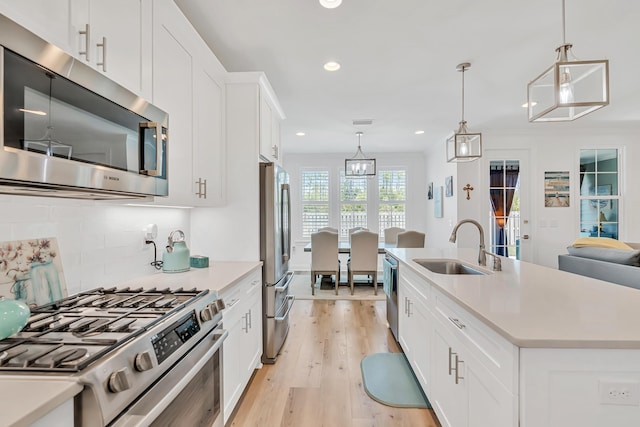 101 Windrow Way Lot 255, Watersound, FL 32461 - kitchen featuring stainless steel appliances, a sink, light wood-style floors, tasteful backsplash, and light countertops