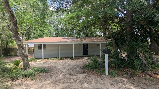single story home featuring fence, metal roof, a porch, and dirt driveway