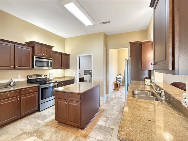 8296 Randall Dr, Navarre, FL 32566 - kitchen with stainless steel appliances, a sink, a center island, light stone counters, and baseboards