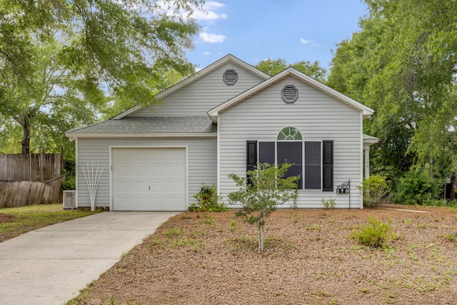 view of front of home with an attached garage, concrete driveway, roof with shingles, and fence
