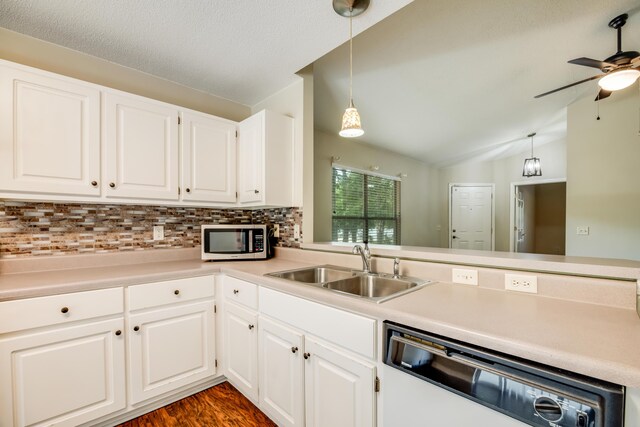 kitchen with dishwashing machine, stainless steel microwave, a sink, lofted ceiling, and backsplash