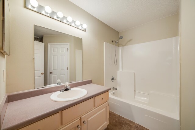 full bath with vanity, washtub / shower combination, and a textured ceiling