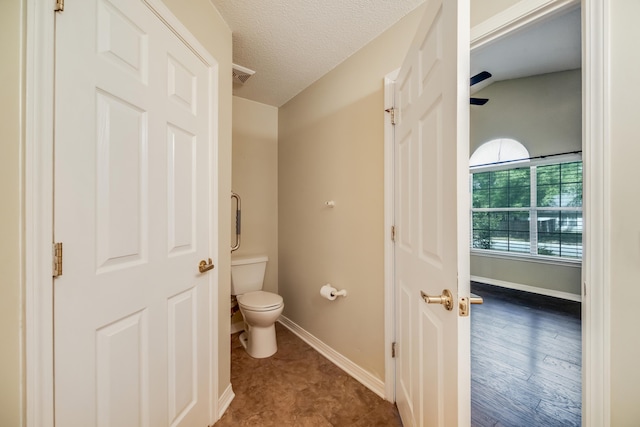 bathroom featuring toilet, baseboards, and a textured ceiling
