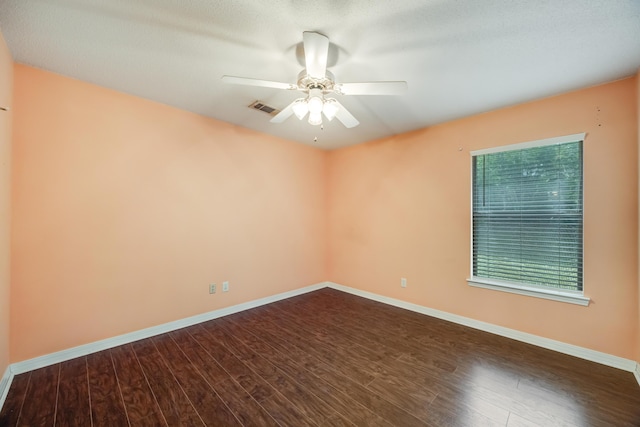 spare room featuring dark wood finished floors, ceiling fan, and baseboards
