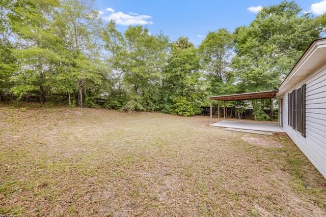 view of grassy yard with a patio and view of scattered trees
