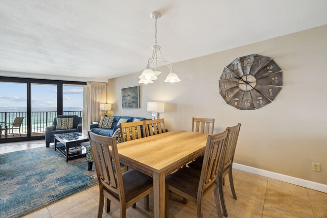 dining space featuring light tile patterned floors, baseboards, and a chandelier