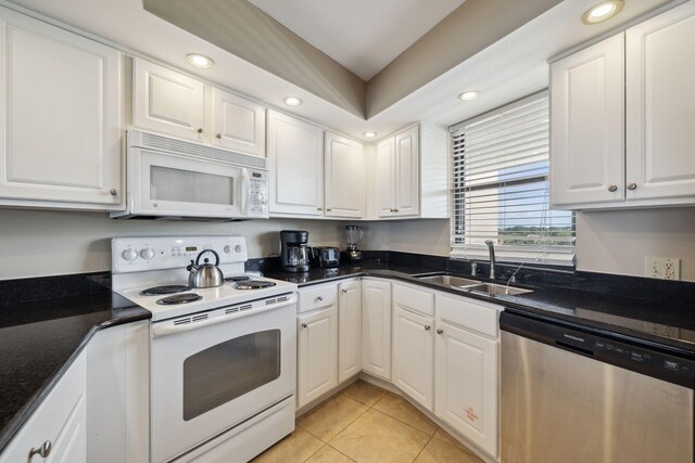 kitchen with white appliances, light tile patterned floors, white cabinets, a sink, and recessed lighting