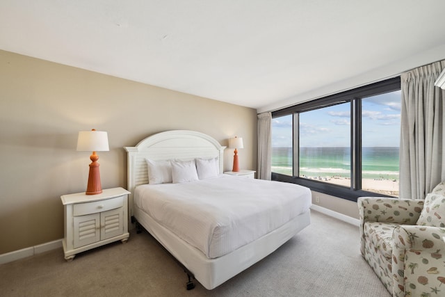 bedroom with carpet, baseboards, and a water view