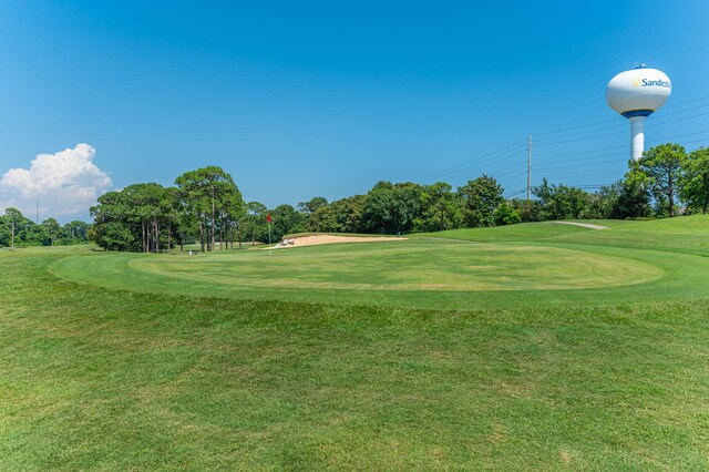 view of home's community with view of golf course, view of scattered trees, and a lawn
