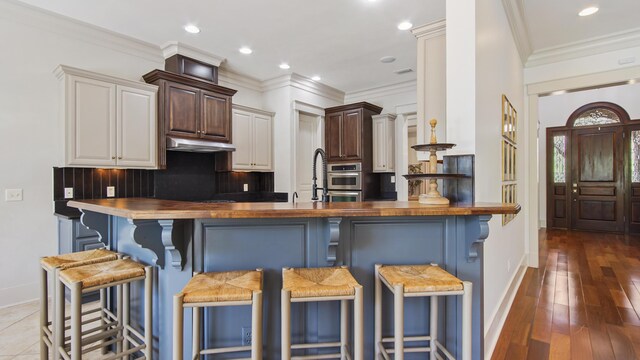 3208 Magnolia Islands Blvd, Panama City Beach, FL 32408 - kitchen with baseboards, butcher block countertops, a breakfast bar area, backsplash, and a peninsula