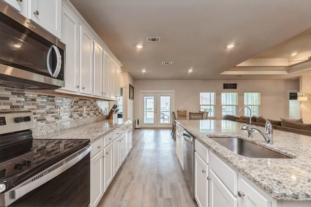514 Mary Lou Way, Crestview, FL 32539 - kitchen with stainless steel appliances, a sink, open floor plan, light wood-style floors, and white cabinetry