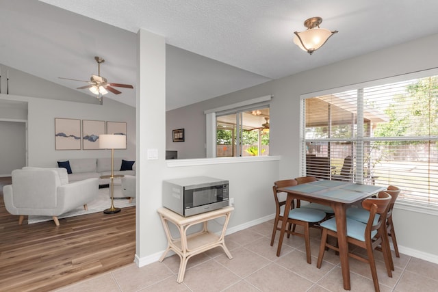 dining space featuring lofted ceiling, baseboards, ceiling fan, and light tile patterned floors