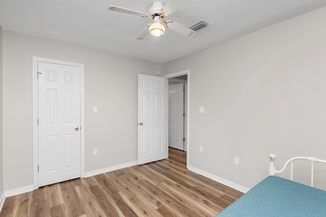 bedroom featuring wood finished floors, baseboards, a ceiling fan, and a textured ceiling