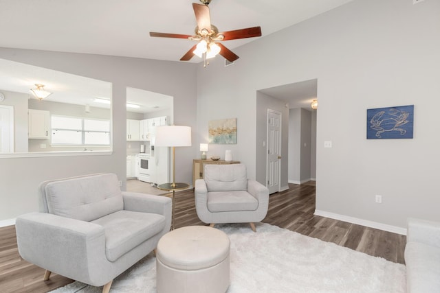 living area with vaulted ceiling, light wood-type flooring, a ceiling fan, and baseboards