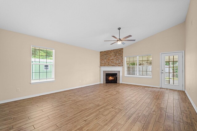 749 Randall Roberts Rd, Fort Walton Beach, FL 32547 - unfurnished living room featuring a ceiling fan, light wood-style flooring, a tiled fireplace, baseboards, and high vaulted ceiling