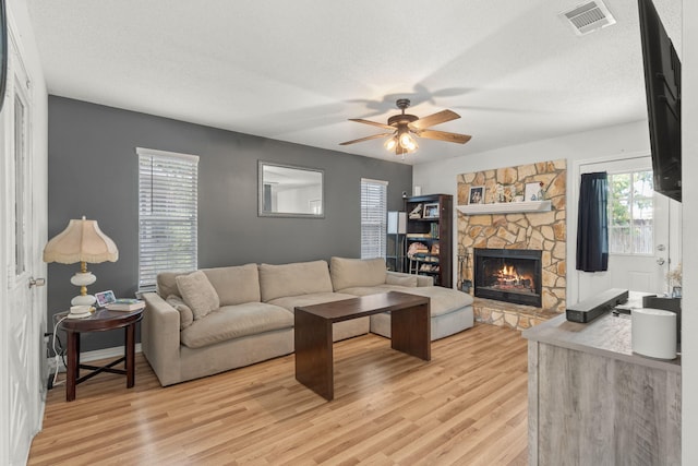 407 Apple Dr, Crestview, FL 32536 - living area with light wood-style floors, ceiling fan, a stone fireplace, and a textured ceiling