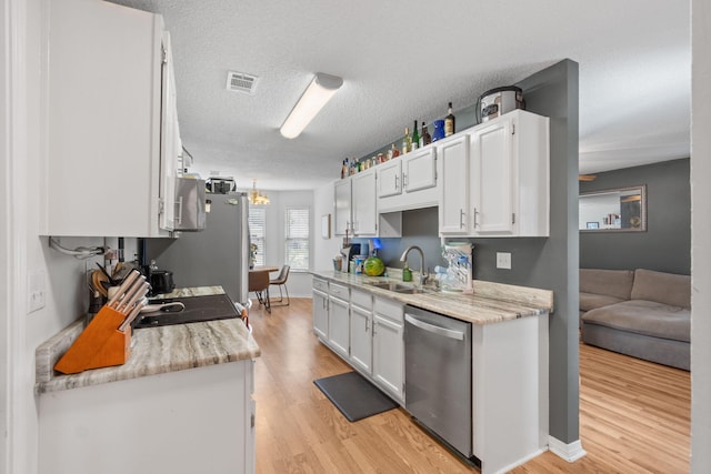 407 Apple Dr, Crestview, FL 32536 - kitchen with stainless steel appliances, a sink, light wood-type flooring, white cabinetry, and a textured ceiling