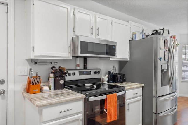 407 Apple Dr, Crestview, FL 32536 - kitchen with stainless steel appliances, wood finished floors, white cabinets, and a textured ceiling