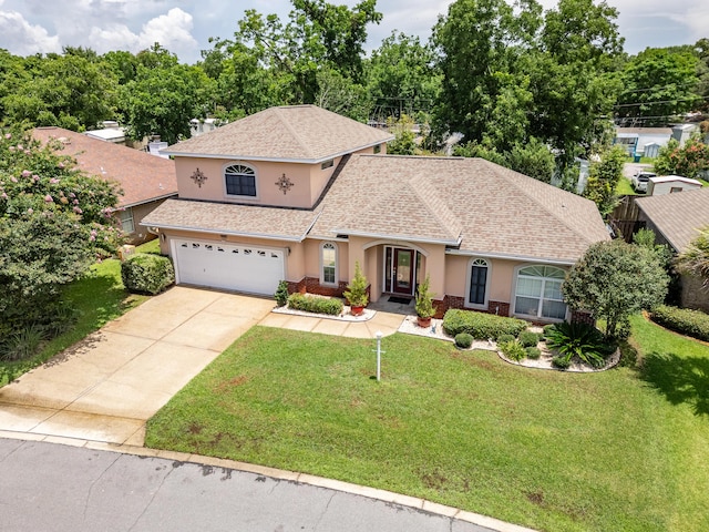 1961 Chesapeake Rdg, Fort Walton Beach, FL 32547 - view of front of house with stucco siding, a garage, driveway, a front yard, and roof with shingles