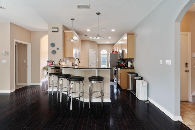 1961 Chesapeake Rdg, Fort Walton Beach, FL 32547 - kitchen featuring stainless steel appliances, light brown cabinetry, a peninsula, dark countertops, and a breakfast bar area