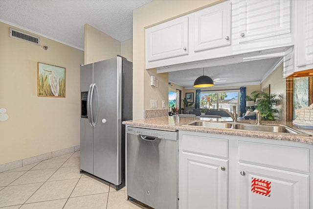 kitchen featuring appliances with stainless steel finishes, a sink, ornamental molding, white cabinets, and light tile patterned floors