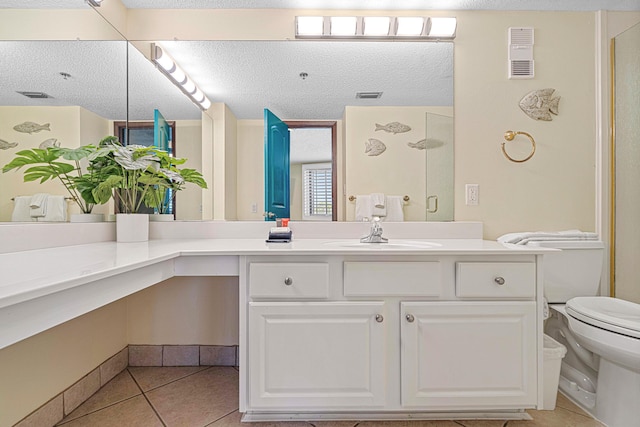 bathroom featuring a shower stall, a textured ceiling, tile patterned floors, vanity, and toilet