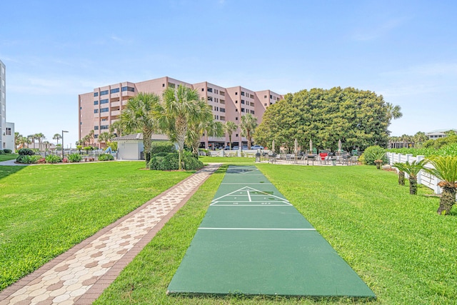 view of property's community featuring shuffleboard and a lawn