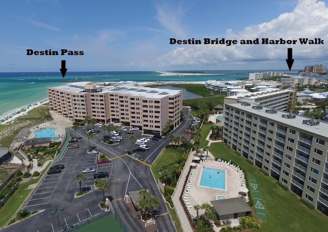 bird's eye view of a pool, a nearby body of water, and apartment complex