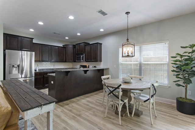 24 Bald Cypress Way, Santa Rosa Beach, FL 32459 - kitchen with appliances with stainless steel finishes, dark brown cabinetry, tasteful backsplash, light wood-type flooring, and a peninsula
