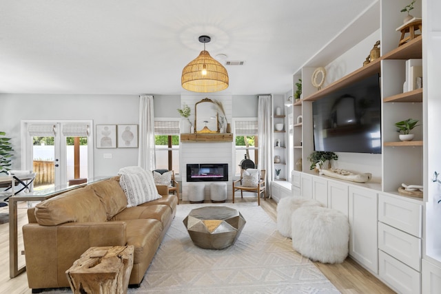 24 Bald Cypress Way, Santa Rosa Beach, FL 32459 - living area featuring healthy amount of natural light, light wood-style flooring, a glass covered fireplace, and french doors