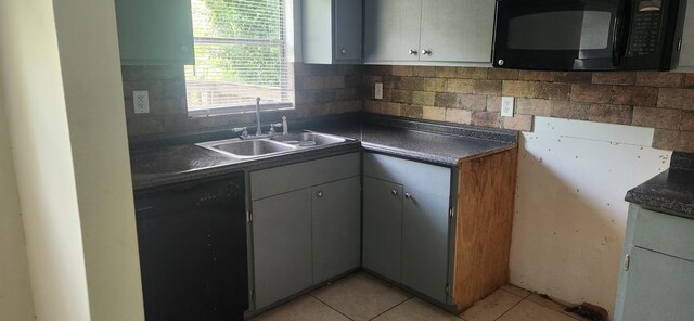 kitchen with black appliances, a sink, light tile patterned flooring, and dark countertops