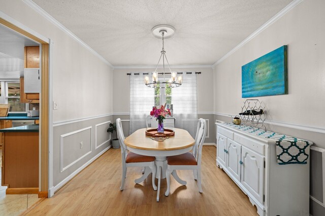 197 Country Club Rd, Shalimar, FL 32579 - dining area featuring a chandelier, ornamental molding, light wood finished floors, wainscoting, and a textured ceiling