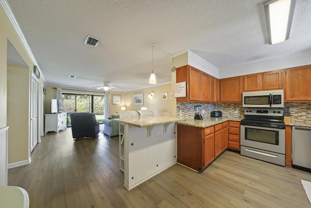 3755 Scenic Highway 98 Unit 1601, Destin, FL 32541 - kitchen featuring stainless steel appliances, open floor plan, light wood-style floors, a peninsula, and crown molding