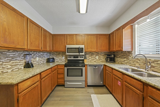 3755 Scenic Highway 98 Unit 1601, Destin, FL 32541 - kitchen with stainless steel appliances, a sink, light wood-type flooring, a textured ceiling, and brown cabinets
