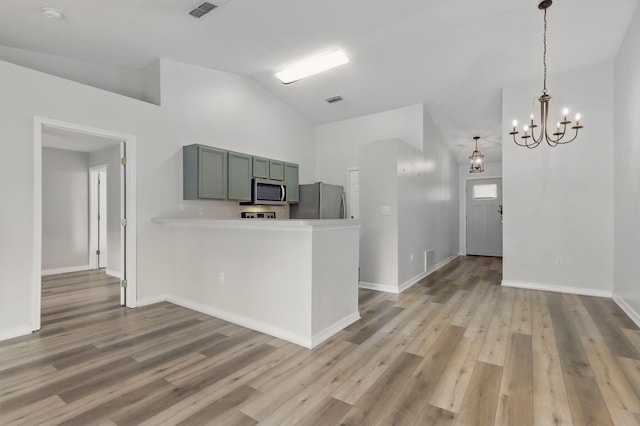 kitchen featuring stainless steel appliances, a chandelier, light countertops, light wood finished floors, and high vaulted ceiling