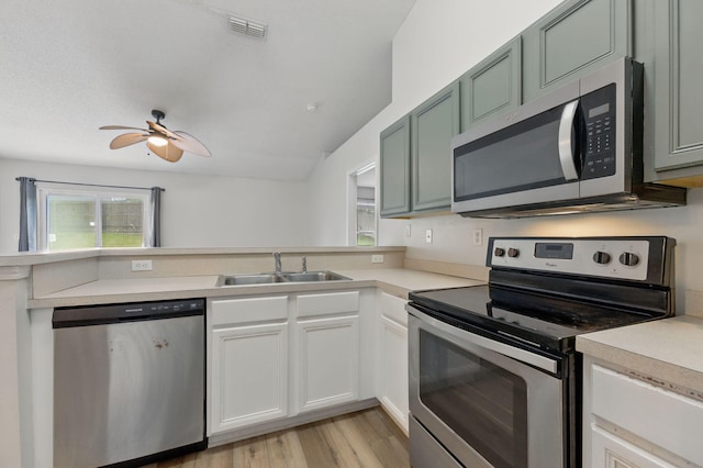 kitchen featuring stainless steel appliances, a sink, a peninsula, light countertops, and a ceiling fan