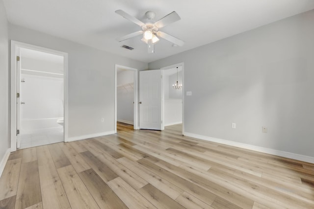 unfurnished bedroom featuring a walk in closet, light wood-type flooring, and baseboards