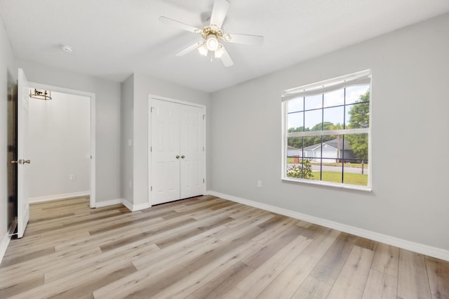 unfurnished bedroom featuring light wood-style flooring, baseboards, a closet, and ceiling fan