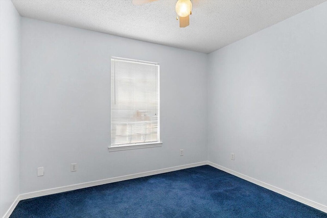 spare room with dark carpet, a ceiling fan, baseboards, and a textured ceiling