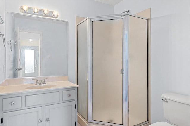 full bathroom featuring a shower stall, toilet, and vanity