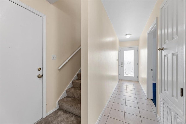 hall with baseboards, light tile patterned floors, and stairs