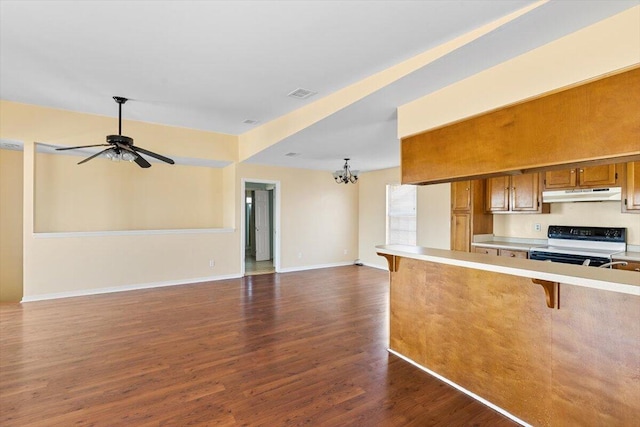 kitchen featuring under cabinet range hood, range with electric cooktop, brown cabinets, dark wood-style flooring, and light countertops