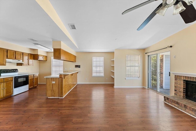 kitchen featuring range with electric stovetop, brown cabinets, under cabinet range hood, and open floor plan