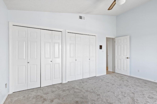 unfurnished bedroom with multiple closets, carpet flooring, lofted ceiling, baseboards, and a ceiling fan