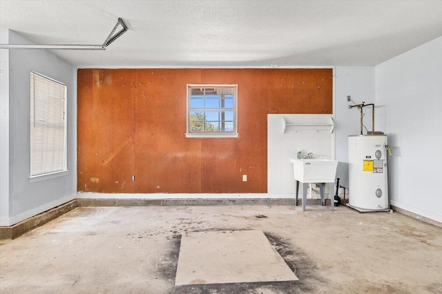 garage featuring electric water heater, baseboards, and a sink